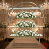 Gold circle ring display rack at luxury wedding ceremony space floral shelves crystal chandeliers