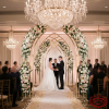 Gold nested arch backdrop at luxury wedding ceremony bride groom crystal chandeliers rose petal aisle