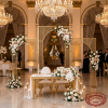 Gold 3-panel gothic arch backdrop behind sweetheart table hotel ballroom crystal chandeliers floral