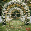Gold arc wine display rack at outdoor garden wedding ceremony with floral arch