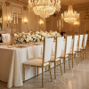 Gold bamboo-node high-back chairs at grand wedding banquet hall dinner table chandeliers
