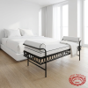 Black iron white velvet bench at upscale hotel minimalist white bedroom natural daylight scrollwork visible