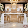 Gold crescent spindle-leg crystal pendant table at hotel wedding ceremony stage white florals chandeliers