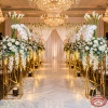 Gold geometric mesh columns as wedding aisle markers with dramatic floral arrangements chandeliers