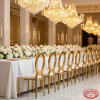 Gold O-ring circular chairs at elegant wedding banquet hall dinner table chandeliers