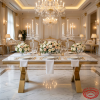 Gold A-leg dining table at luxury hotel banquet hall marble top white linen floral chandeliers