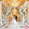 Large silver round arch decorated with white peonies roses couple beneath chandeliers wedding ceremony
