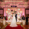 Gold diamond lattice floral backdrop at luxury wedding ceremony stage crystal chandeliers couple