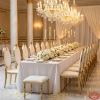 Gold large leaf-back luxury chairs at grand wedding banquet hall table chandeliers column legs