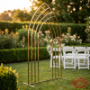 Gold nested arch frame at outdoor garden wedding terrace golden hour greenery hedge backdrop