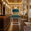 White frame green velvet bar stool at grand luxury hotel bar warm golden lighting dark wood counter