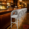Grey upholstered bar stools lined at upscale hotel bar counter warm amber bokeh ambiance