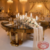 Gold ornate carved skirt round table at hotel ballroom wedding dinner acanthus detail visible 45 degree
