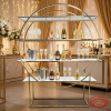 Gold ring white shelf display at elegant champagne wedding bar bottles flutes warm ambiance