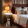 Silver marble top hourglass side table in luxury hotel suite plush bedding warm amber lamp