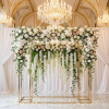 Gold rectangular display frame at wedding backdrop area with hanging white rose garlands chandeliers