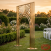 Gold Art Deco arch at outdoor garden wedding golden hour greenery hedge backdrop lush