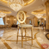 Gold O-ring bar stool at grand luxury hotel lobby bar marble columns crystal chandeliers gold lighting