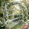 Silver X-brace display rack at outdoor garden wedding floral arch bokeh