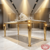 Gold angled splayed leg dining table side view hotel restaurant marble floor warm spotlights