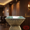 Gold square cocktail table at modern boutique hotel bar lounge dark wood amber lighting