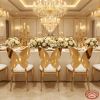 Gold butterfly wing back chairs at wedding banquet hall dinner table chandeliers