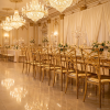 Gold radial arc-bar backrest chairs from behind hotel ballroom wide row ornate pattern repeating